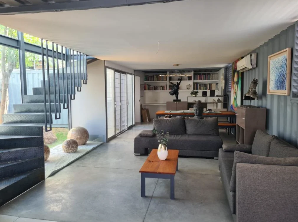 Interior de casa en contenedor con sala, cocina y ventanales